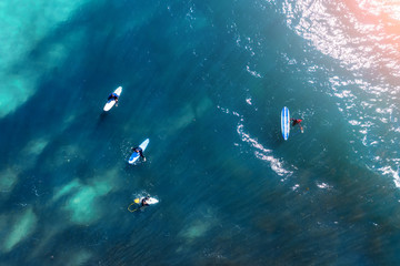 Surfers on the water in the bay in anticipation of a big wave, aerial top view.