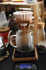 Brewing coffee in pink ceramic origami dripper on wooden stand. Alternative manual brew. Electronic scale