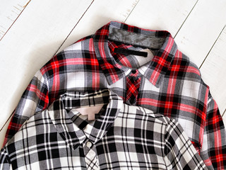 Two checkered shirts on a wooden background. Top view. Close up