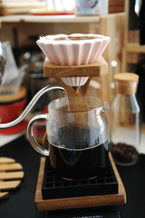 Brewing coffee in pink ceramic origami dripper with bypass. Wooden stand. Alternative manual brew