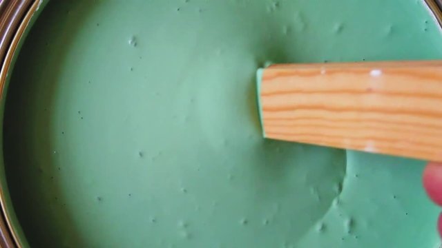 Slow motion of a person mixing green paint in a can ready to decorate