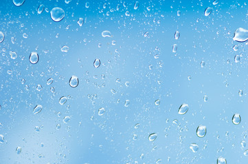 Fototapeta na wymiar Water drops of rain on blue glass background