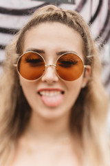 A beautiful woman in her twenties wearing 70s style clothing and sunglasses posing for portraits and smiling 