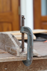 Old c-clamp use for clamped pieces of wood in carpentry workshop.