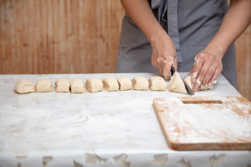 The hostess cuts the dough in the kitchen