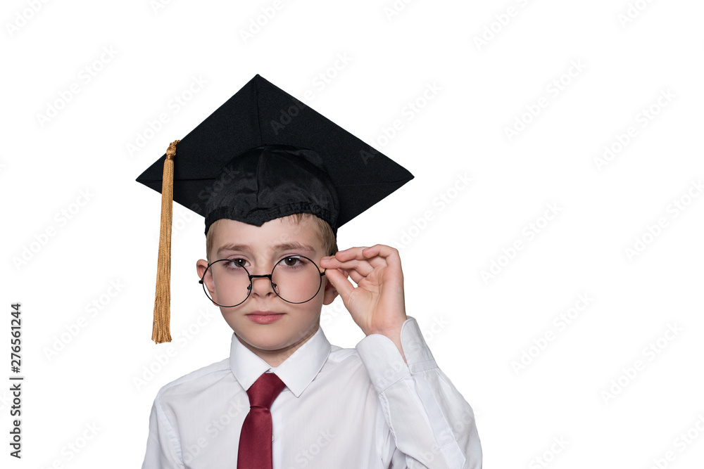 Wall mural boy in a square academic cap and white shirt correcting glasses. school concept. isolate