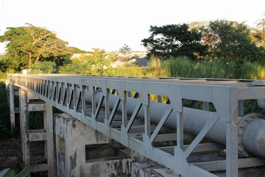 Large gray steel plumbing pipe on pipe-bridge.