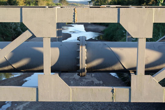 Large gray steel plumbing pipe on pipe-bridge.
