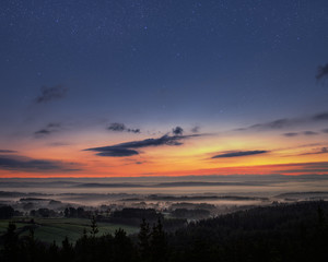 Naklejka premium Starry dawn over a misty landscape