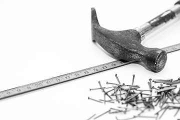 Hammer,  tape measurer, small nails, conceptual construction, renovation image in black and white, copy space.