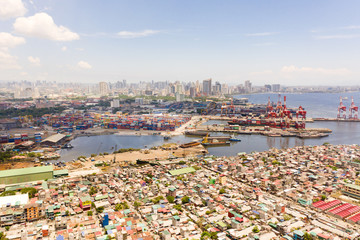 Fototapeta na wymiar Port in Manila, Philippines. Sea port with cargo cranes. Cityscape with poor areas and business center in the distance, view from above. Asian metropolis.
