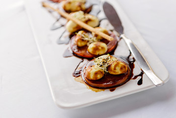 Served table at the banquet. Slices of tomatoes with mushrooms in balsamic sauce