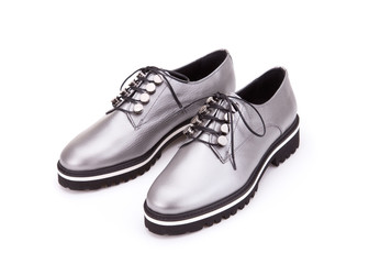 A pair of silver shoes on a cord. Silver shoes from silvery skin isolate on a white background.