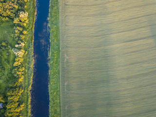 Aerial view over rural landscape in a warm summer sunset tones. Agriculture land mixing with forest...