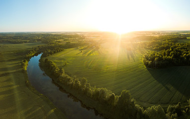 Aerial view over rural landscape in a warm summer sunset tones. Agriculture land mixing with forest...