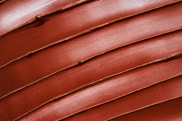 Smears and texture of bronze lip gloss isolated on white background