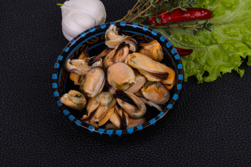 Pickled mussels in the bowl served pepper, garlic and salad