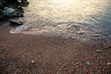 Summertime evening sand and pebbles of the Aponissos beach, Agistri island, Saronic gulf, Greece.