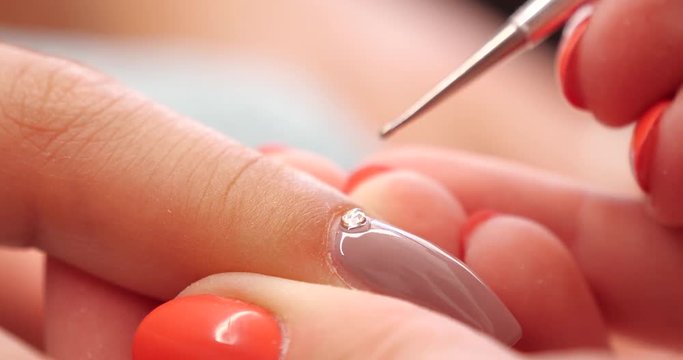 Close up of Beautician Putting a Strass on the Nail in Beauty Manicure Salon
