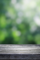 Fototapeta premium Blurred abstract green bokeh and wooden table background.