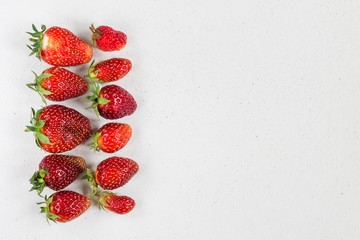 Ugly organic fresh strawberries grown in the garden, on white stone background, with a copy of the space. Can be used as a healthy Breakfast.