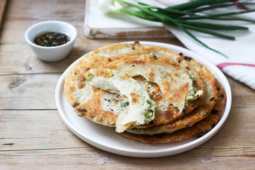 Homemade appetizing scallion pancakes and a bunch of green onions. Rustic style.