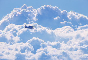 Small seaplane flying over stormy clouds 