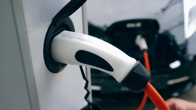 One man charges his electric car at a modern station. Electric vehicle charging.