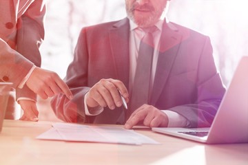 Midsection of business colleagues discussing over document at desk in office