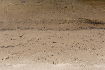 brown textured surface with sand and water with copy space