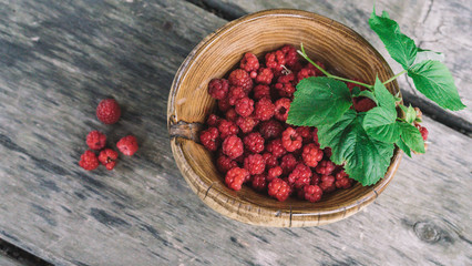 organic fresh raspberries in a wooden bowl on old wooden table background. Rustic style.