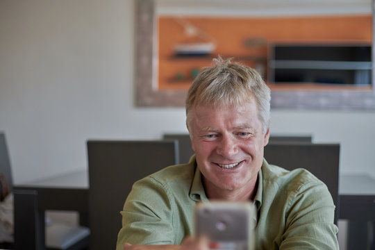 Middle-aged handsome man at home with smart phone mobile