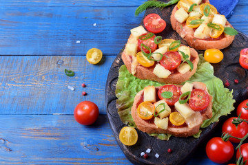 Bruschetta with different sorts of cherry tomatoes and soft cheese on the blue table