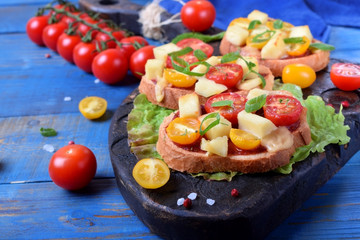 Bruschetta with different sorts of cherry tomatoes and soft cheese on the blue table