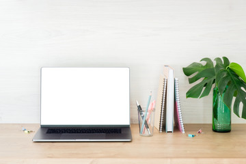 Laptop computer with white blank screen, stationery and Monstera leaves on work table. Business and education concept. Fashion blogger workspace.