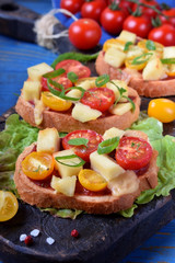 Bruschetta with different sorts of cherry tomatoes and soft cheese on the blue table