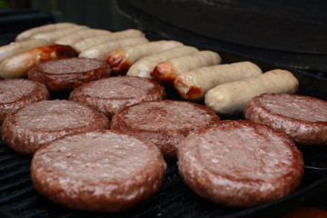 Burgers and sausages starting to cook on a grill
