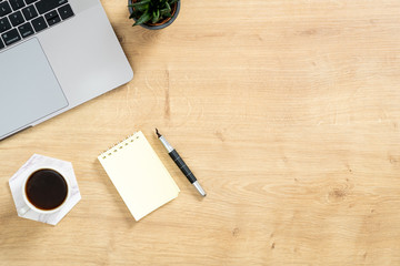 Wood office desk table with laptop computer, cup of coffee and supplies. Top view with copy space, flat lay. Feminine workspace concept.
