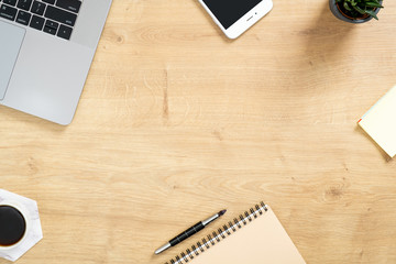 Wood office desk table with laptop computer, cup of coffee and supplies. Top view with copy space, flat lay. Feminine workspace concept.