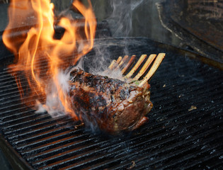 Rack of lamb on barbecue with flame and smoke