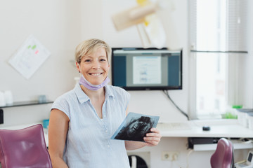 lächelnde Zahnärztin schaut sich ein Röntgenbild an