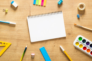 School notebook and various stationery on a wooden desk table. Back to school concept. Flat lay style composition, top view, overhead.