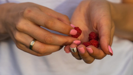 woman holding red raspberrie in hands.