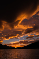 Cielo con nubes color naranja despues de la tormenta y el lago calmado