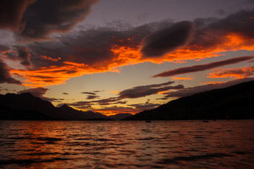 Atardecer con cielo naranja y nubes que se reflejan en el lago