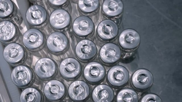 Pharmaceutical automatic production line machine conveyor with empty glass bottles at pharmacy processing factory. Pharma industry, medicine, manufacturing and automated technology equipment concept