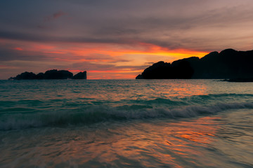Atardecer de cielo naranja y el reflejo en el mar y la playa.