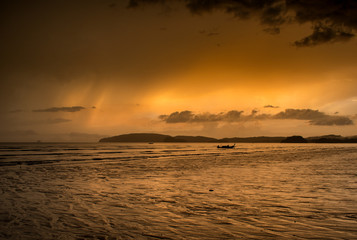 Atardecer y tormenta, cielo naranja y playa vacia