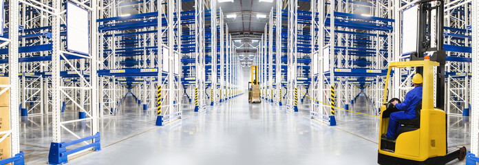 Huge distribution warehouse with high empty shelves and forklift with driver. © hacohob