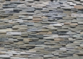 Stone wall cladding made of uneven natural rock strips of different colors